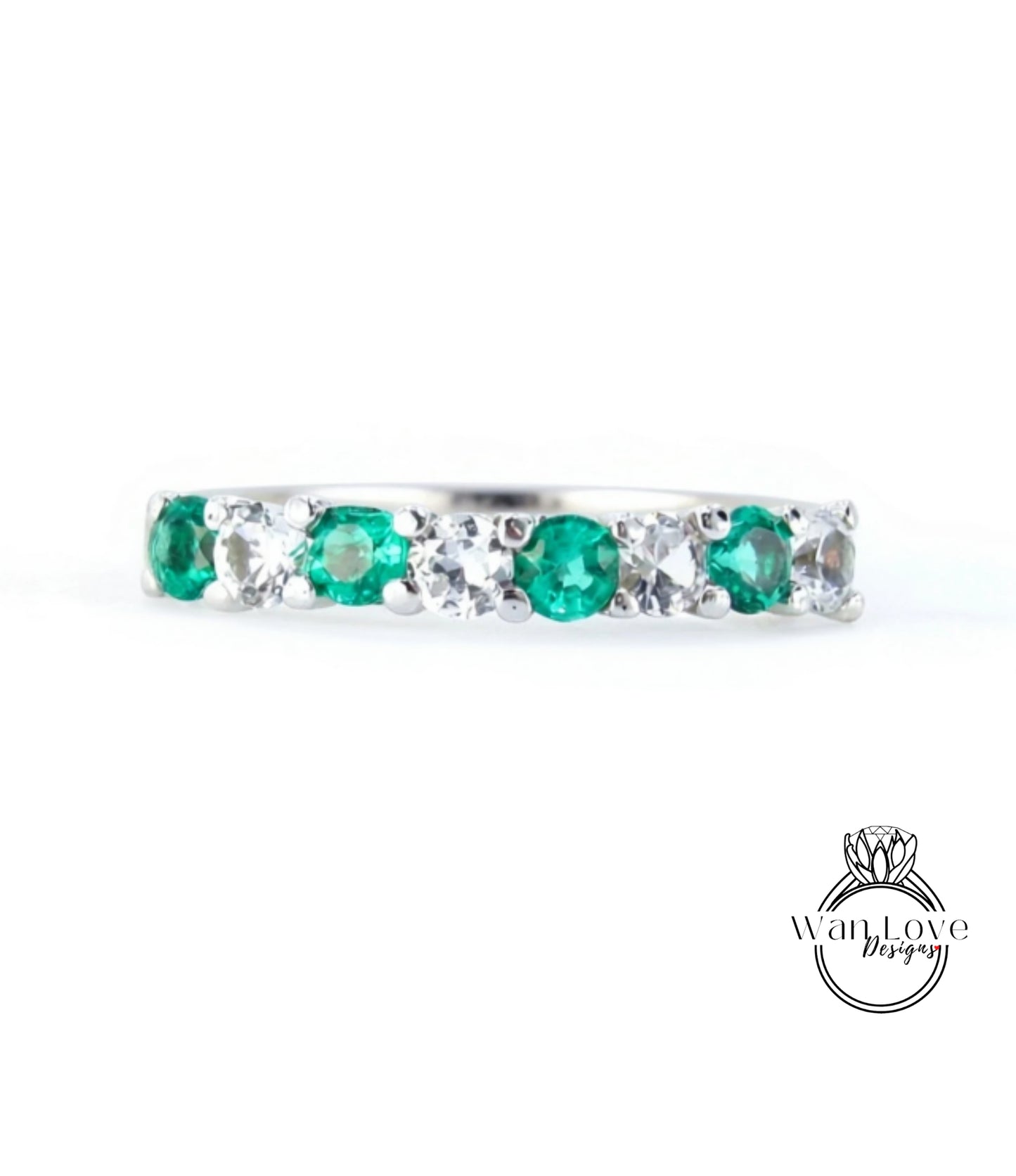 A silver ring with a row of green and white gemstones, including diamonds, set in a band.