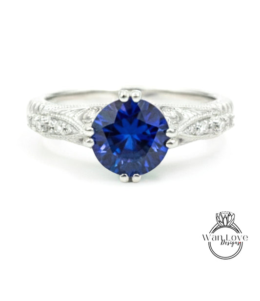 A silver ring with a large blue gemstone, likely a sapphire, as the centerpiece.