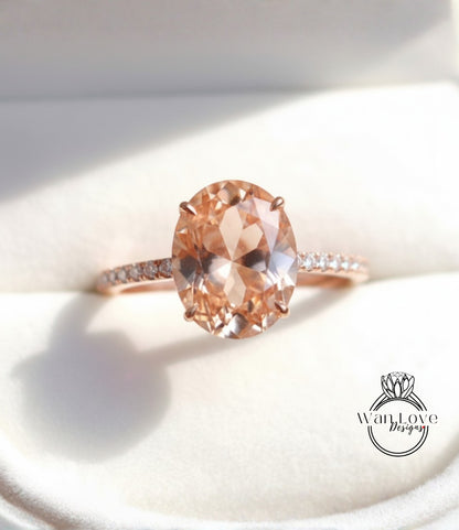 A close-up image of a rose gold engagement ring with a large oval-shaped gemstone set in the center.