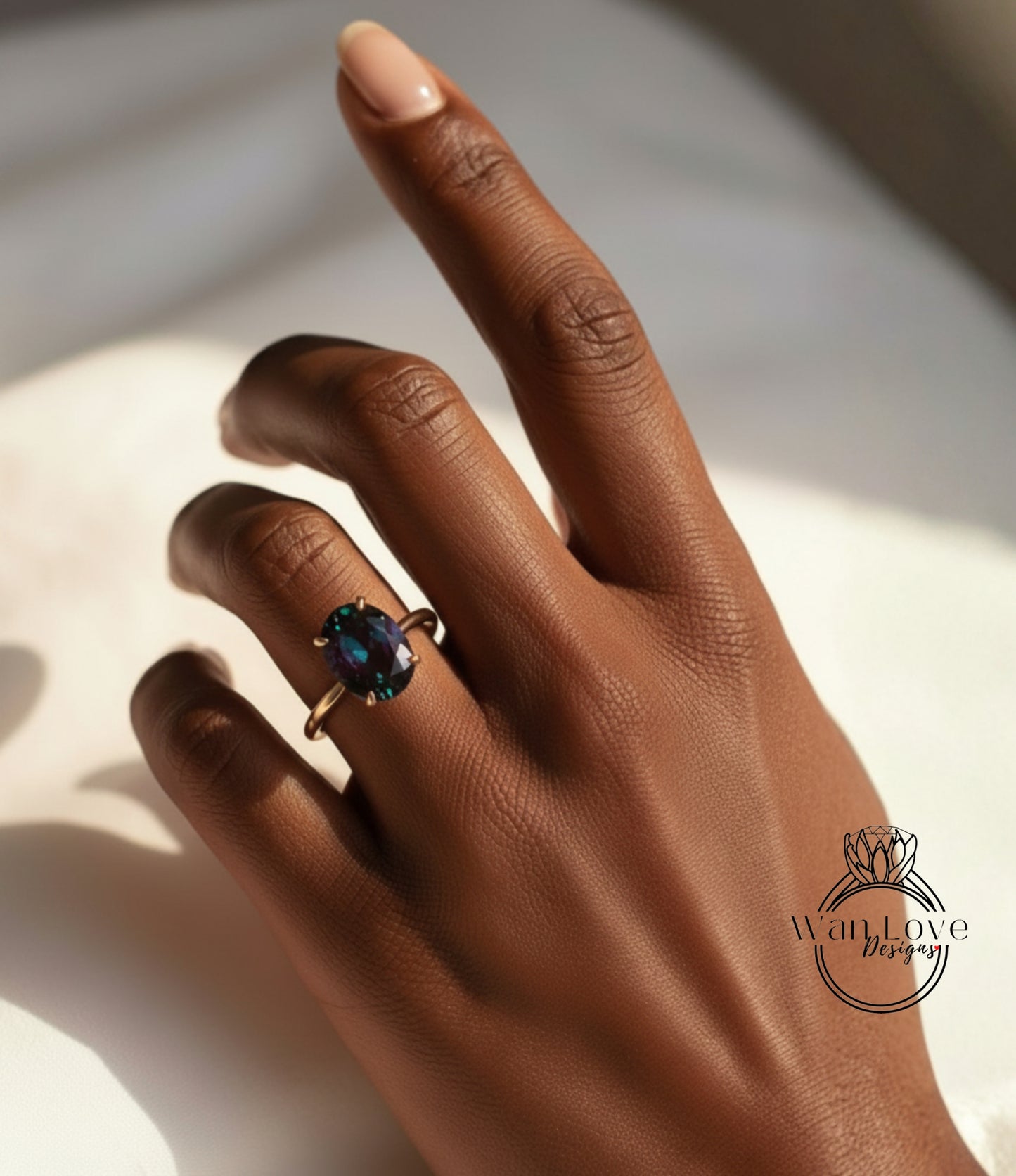 A close-up of a hand wearing a gold ring with a large blue gemstone, resting on a white surface.