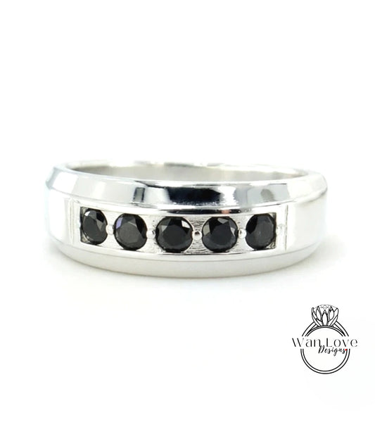 A silver ring with a row of black diamonds set in the band.