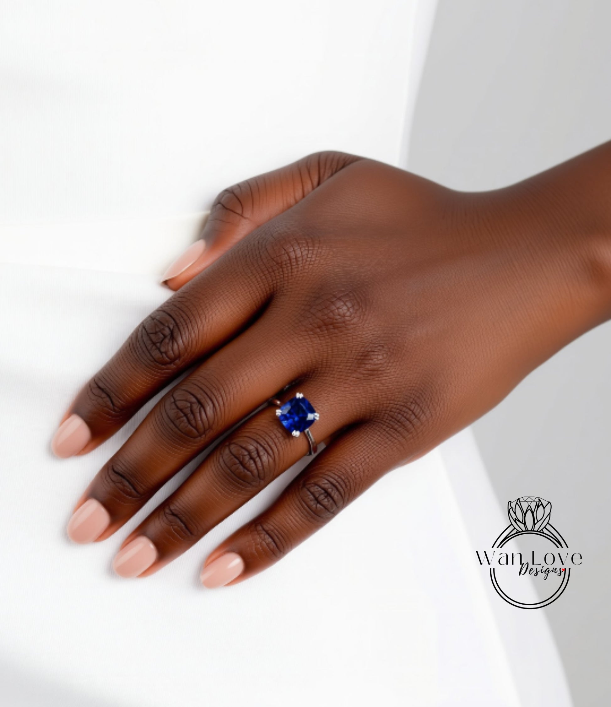 A close-up of a hand wearing a ring with a blue gemstone.