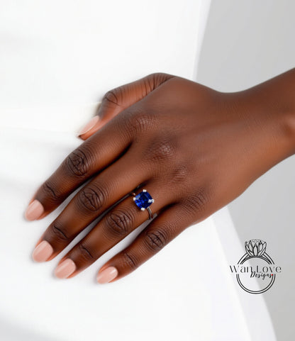 A close-up of a hand wearing a ring with a blue gemstone.