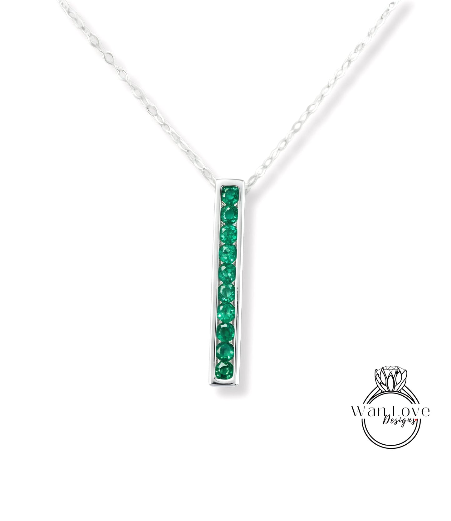 A silver necklace with a vertical rectangular pendant featuring green gemstones.