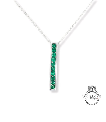 A silver necklace with a vertical rectangular pendant featuring green gemstones.