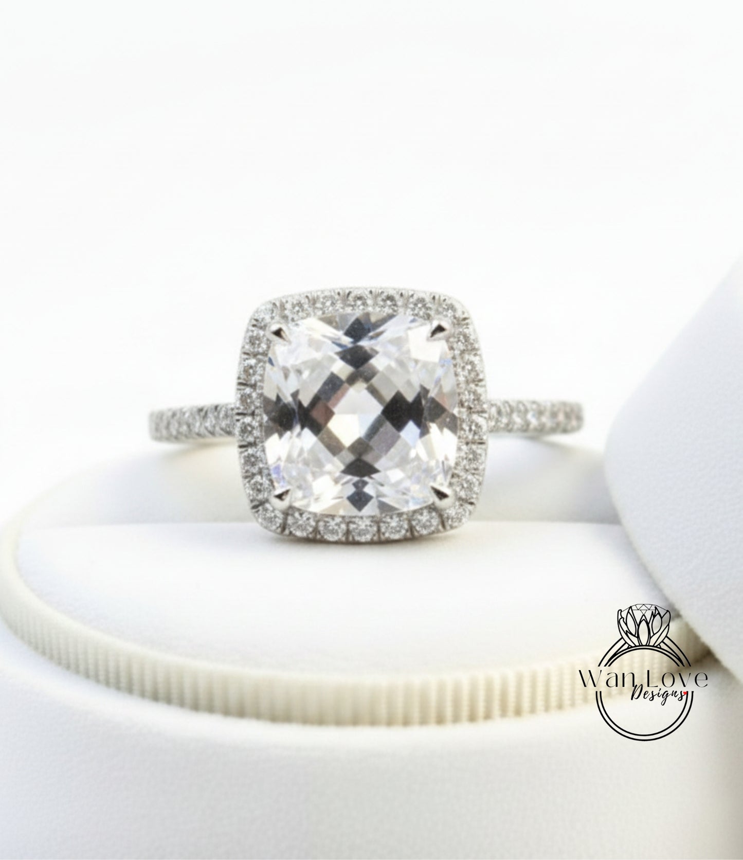 A diamond engagement ring with a large, clear gemstone set in a halo of smaller diamonds, displayed on a white background.