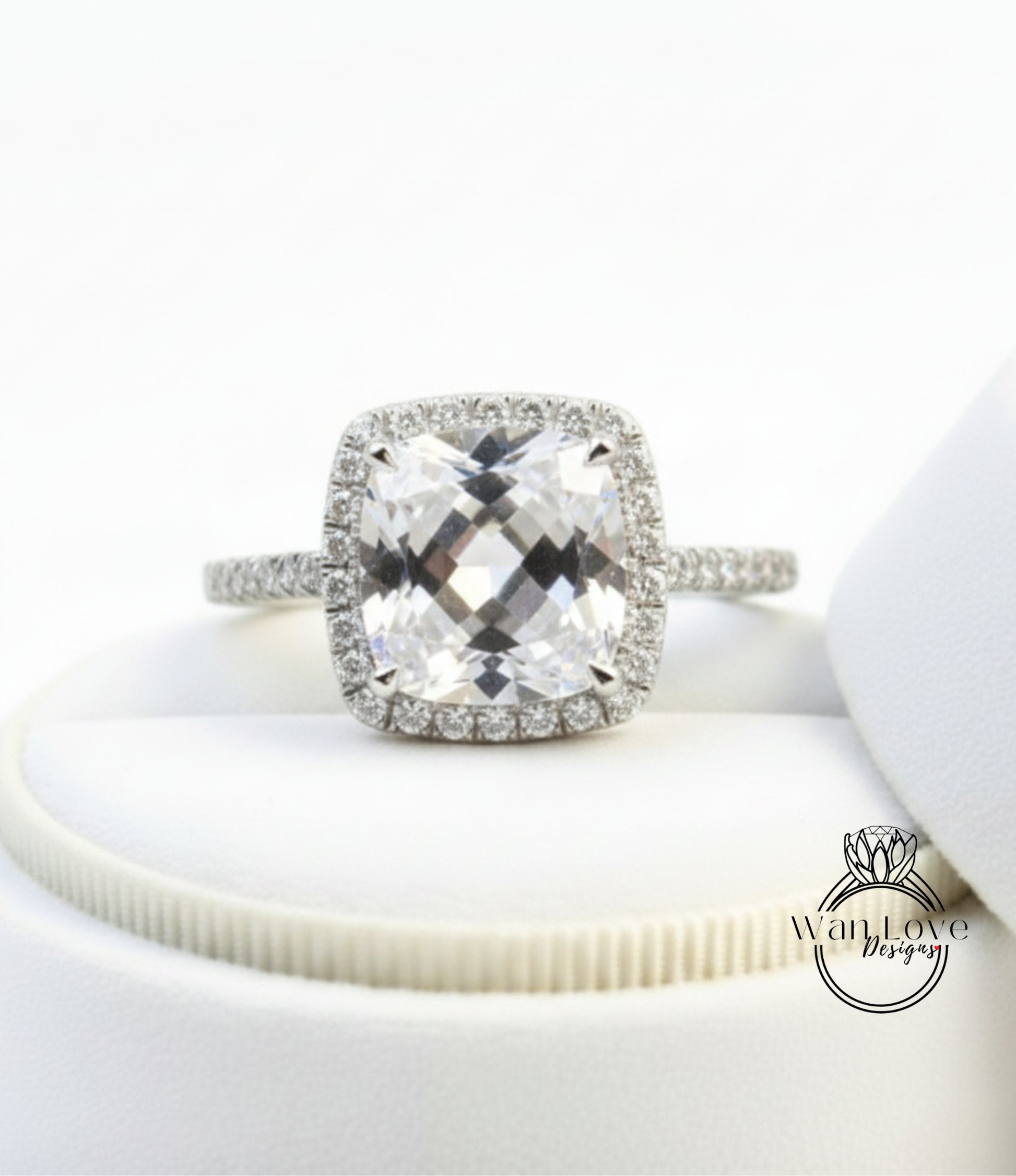 A diamond engagement ring with a large, clear gemstone set in a halo of smaller diamonds, displayed on a white background.