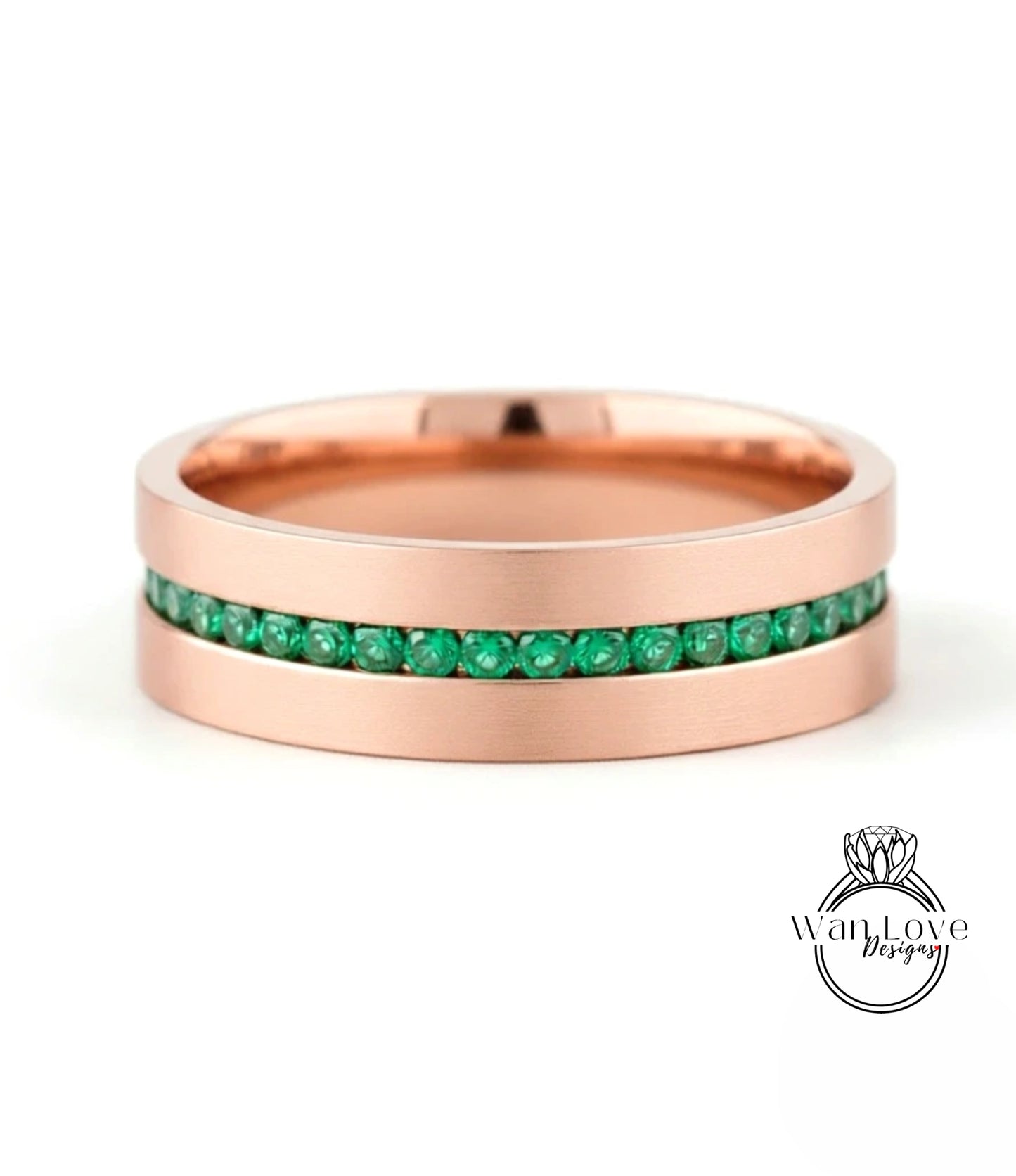 A rose gold band with a row of green gemstones set in it.