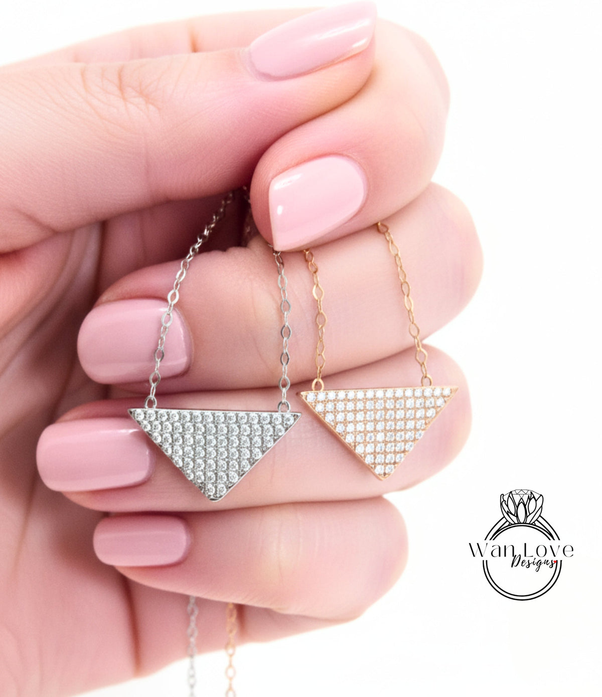 A hand holding two diamond-encrusted necklaces against a white background.