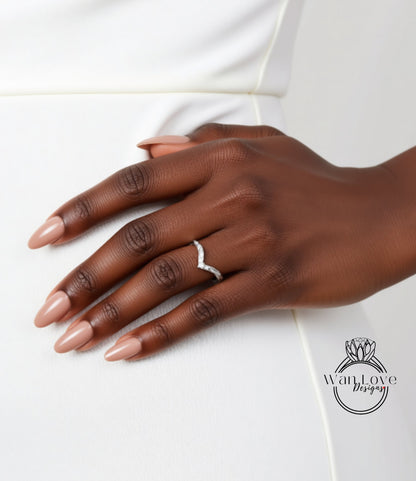 A close-up of a hand wearing a ring on the ring finger, with a white dress visible in the background.
