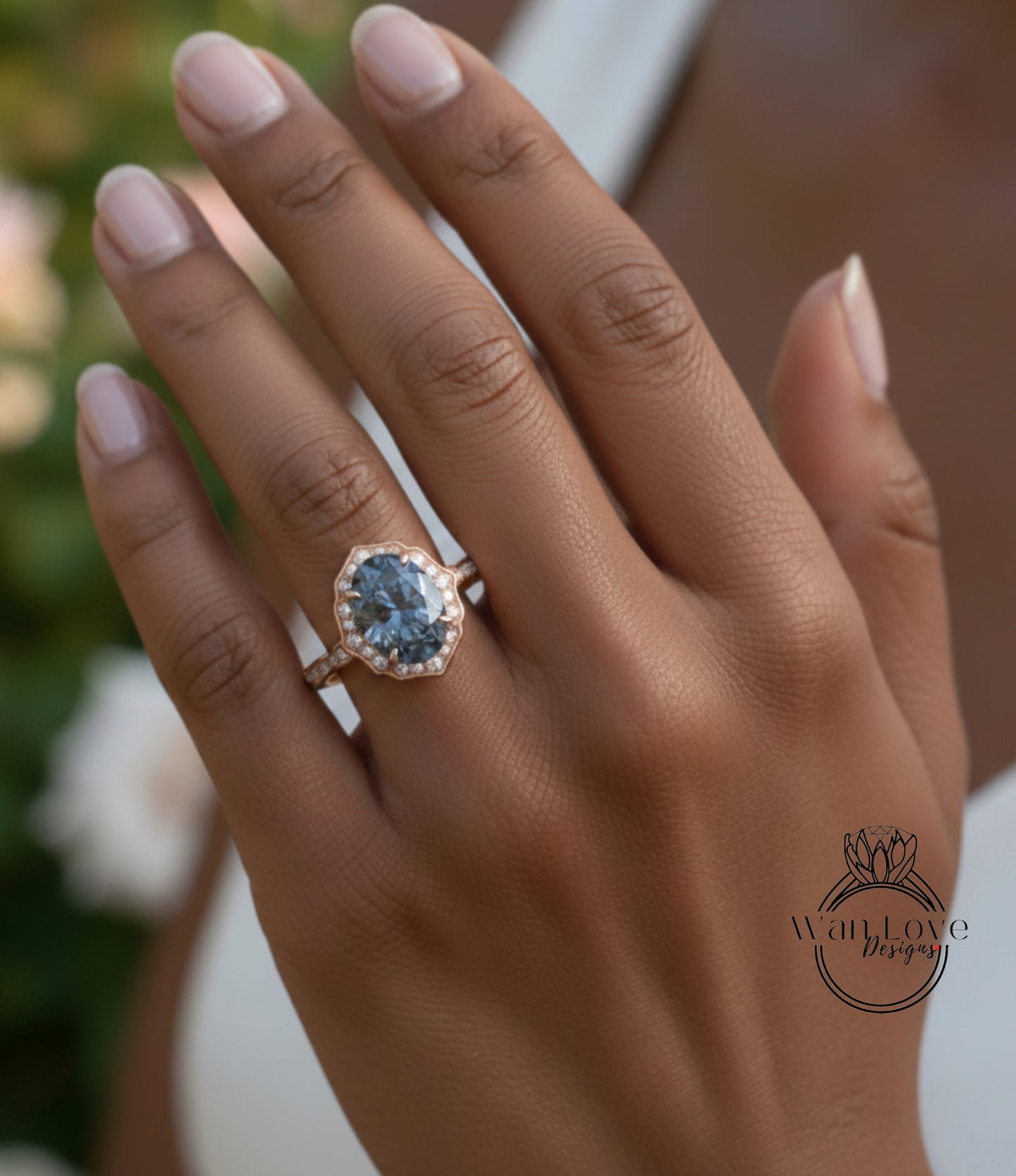 A close-up of a person's hand wearing a gold ring with a large blue gemstone, likely an oval-shaped gemstone.