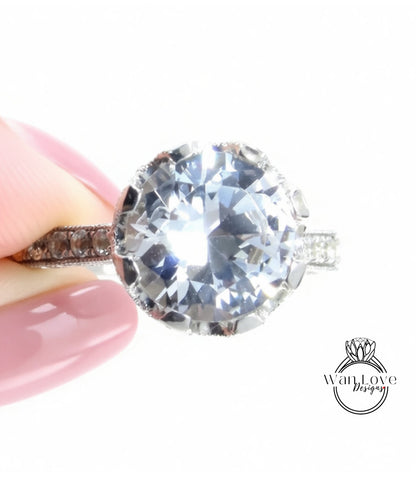 A close-up of a person's hand holding a large, sparkling diamond ring with a halo of smaller diamonds around the center stone.