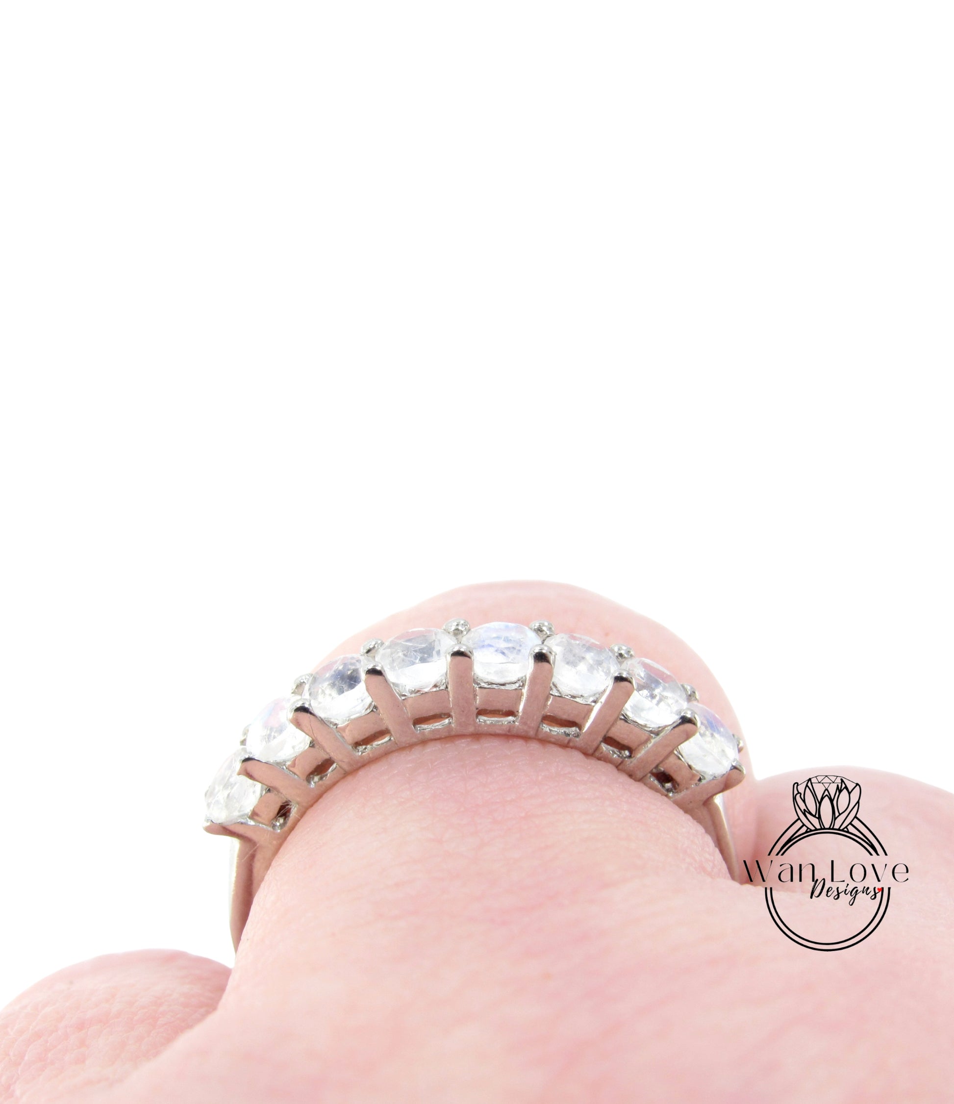 A close-up view of a person's hand wearing a silver ring with a row of clear gemstones.