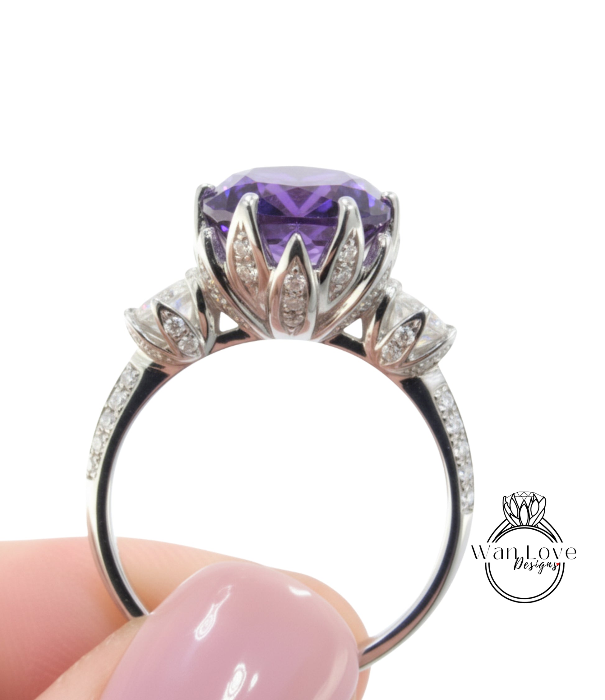 A close-up image of a person's hand holding a silver ring with a large purple gemstone, likely an amethyst, surrounded by smaller diamonds.