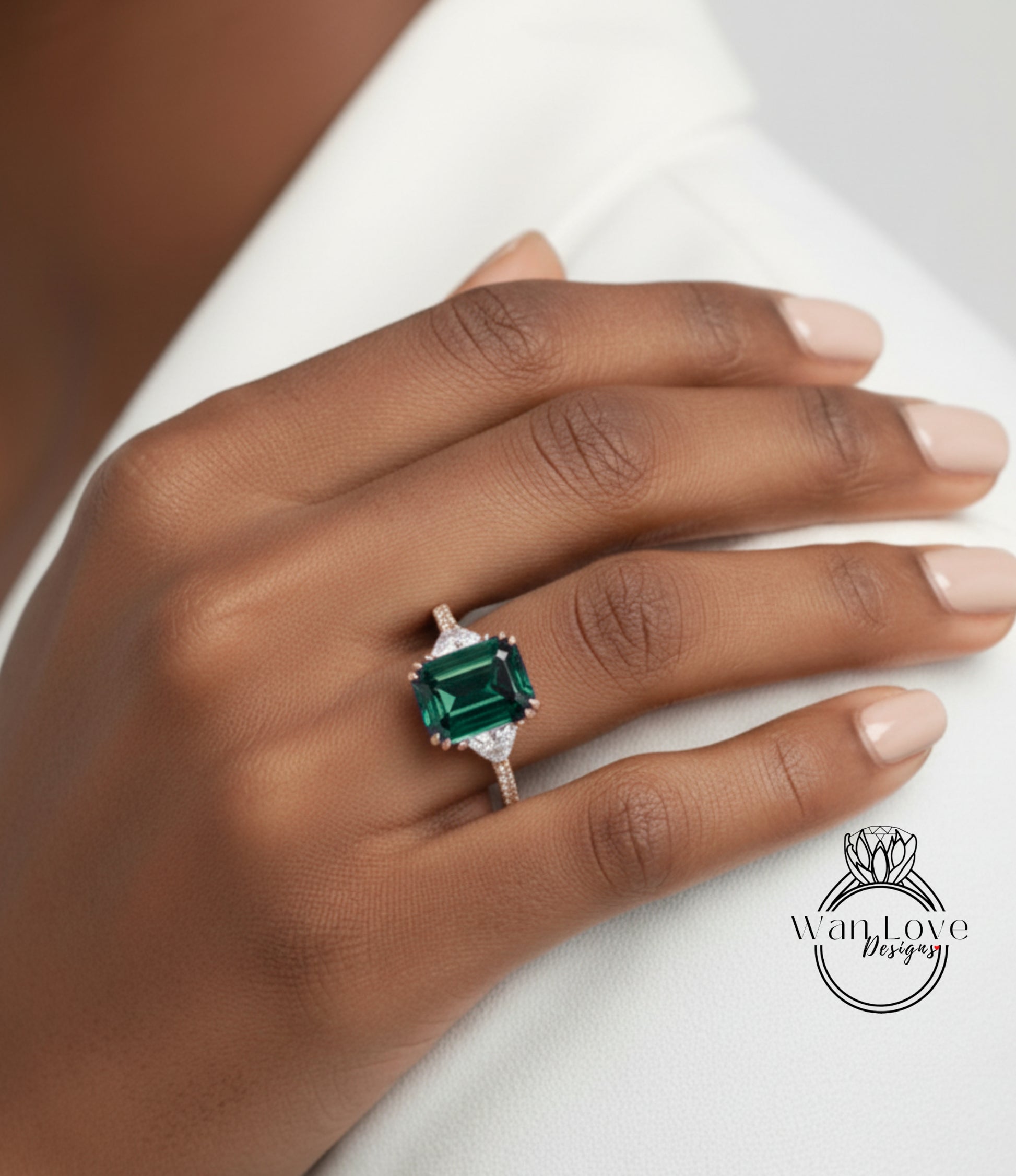A close-up of a hand wearing a ring with a large green gemstone.