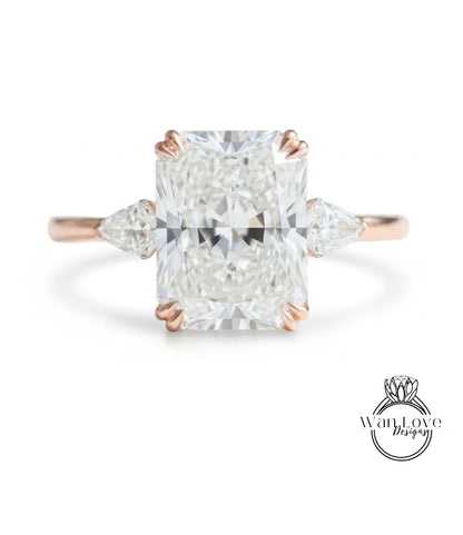 A large, clear diamond engagement ring with a prominent central diamond surrounded by smaller diamonds on either side.