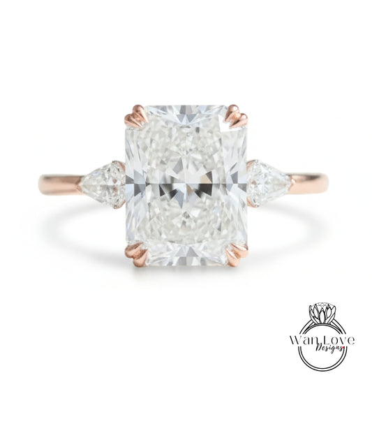 A large, clear diamond engagement ring with a prominent central diamond surrounded by smaller diamonds on either side.