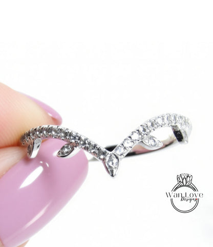 A close-up image of a person's hand holding a silver ring with a decorative design featuring small diamonds.