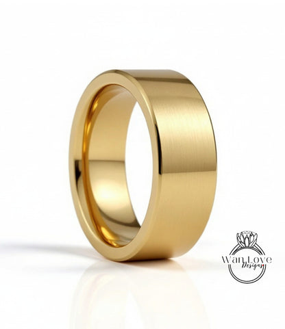 A gold-colored ring with a smooth, shiny surface sits on a reflective surface against a white background.