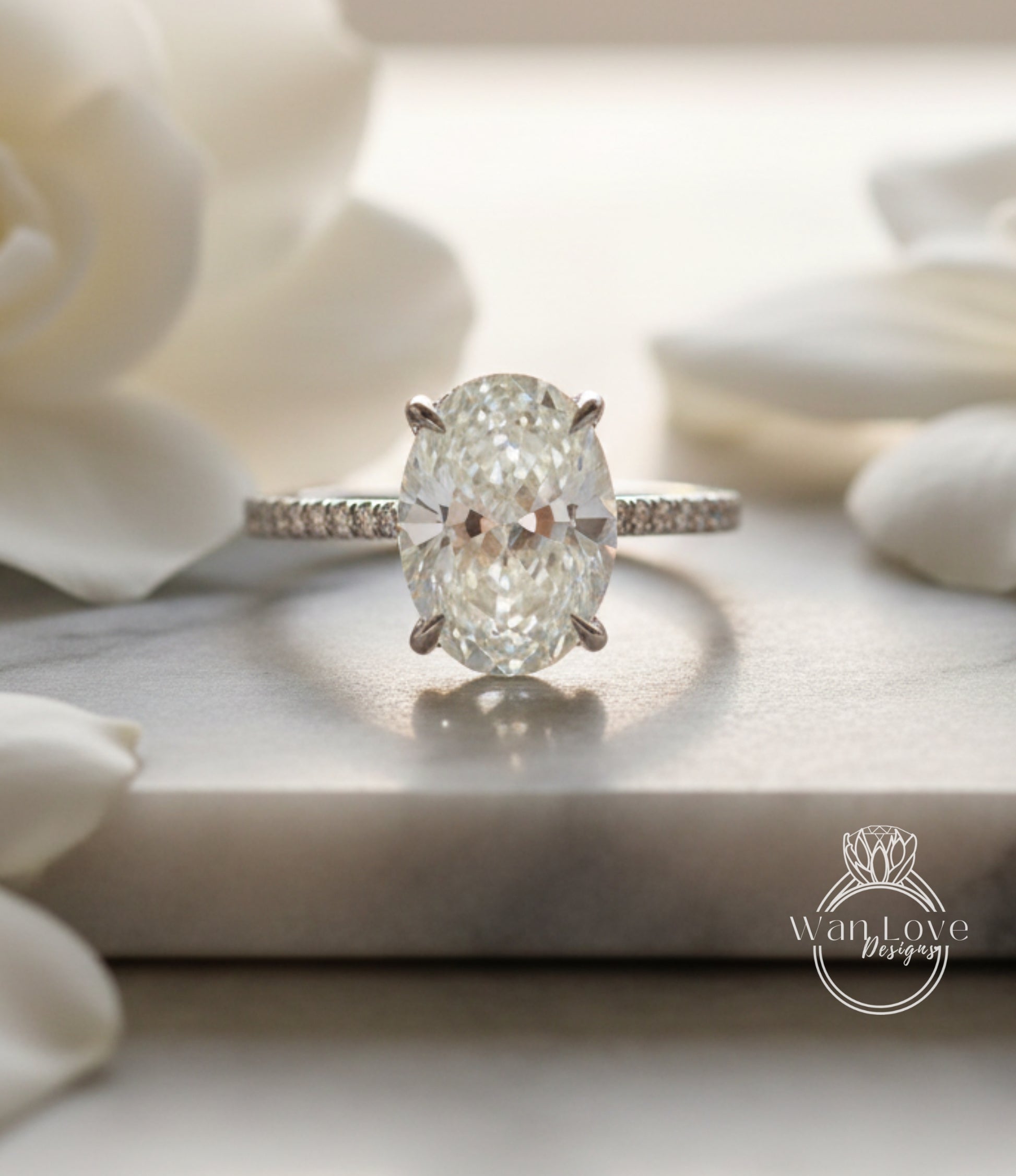 A diamond engagement ring with a large oval-shaped diamond set in a solitaire ring band, surrounded by white flowers.