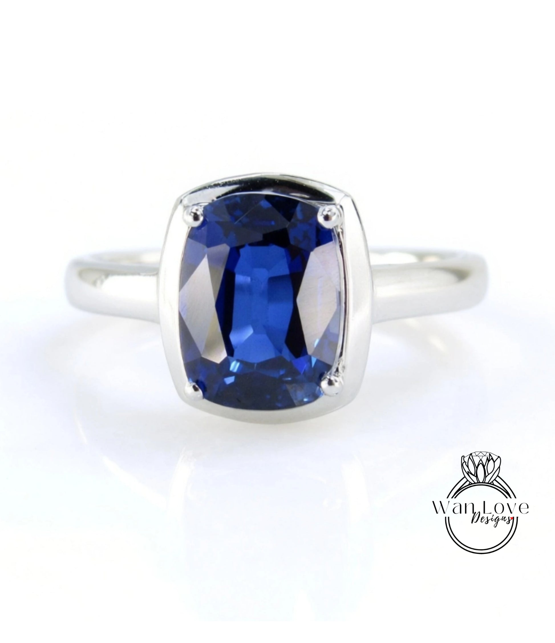 A silver ring with a large, deep blue sapphire gemstone set in the center.