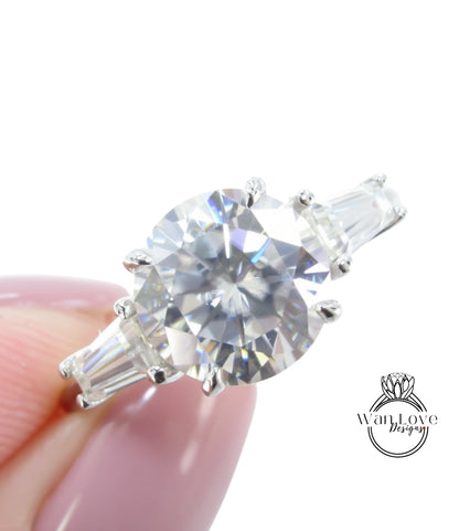 A close-up of a diamond engagement ring being held in someone's hand, showcasing the sparkling center stone surrounded by the band and accents.