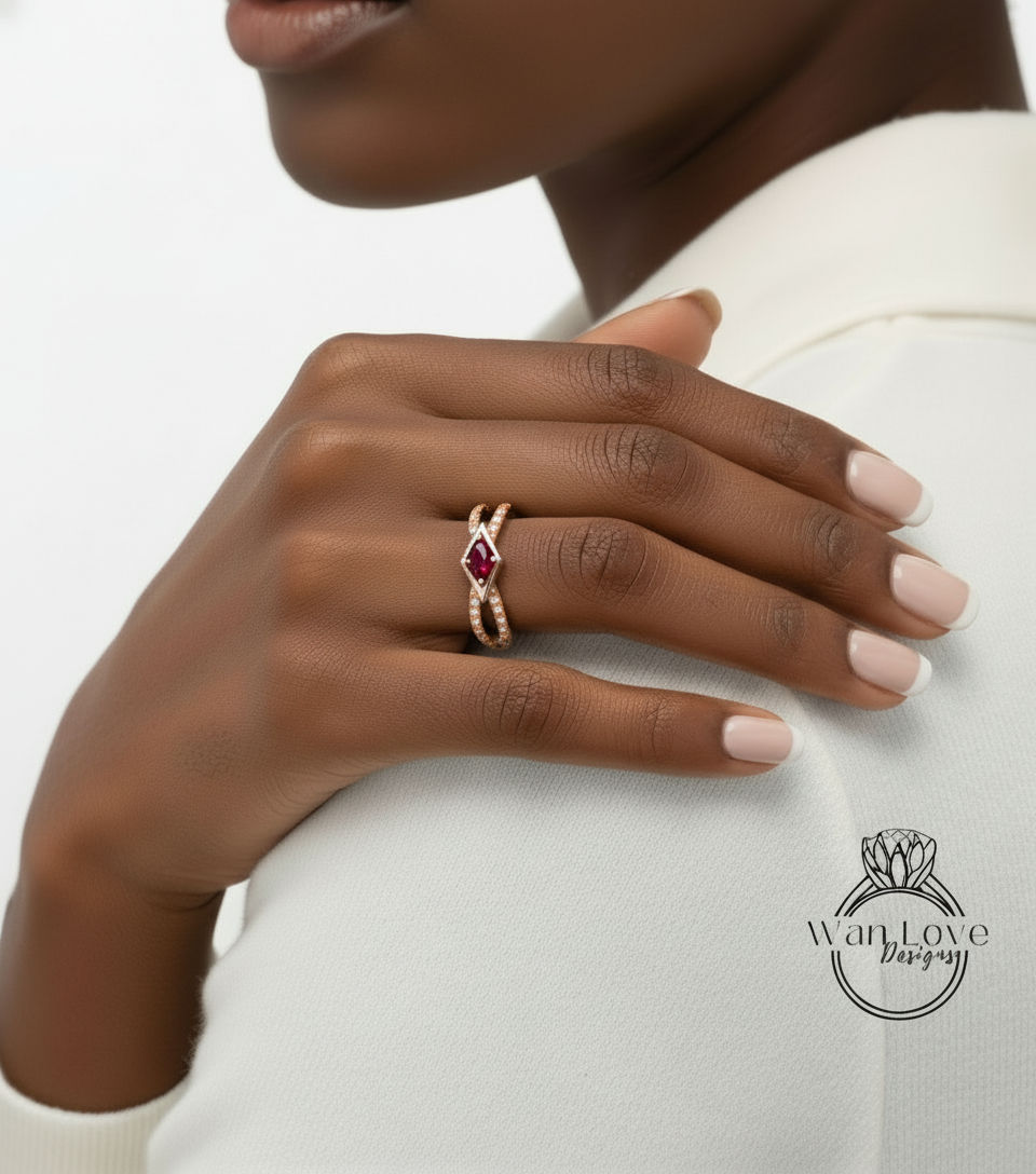 A close-up of a person's hand wearing a gold ring with a red gemstone, resting on a white shirt.
