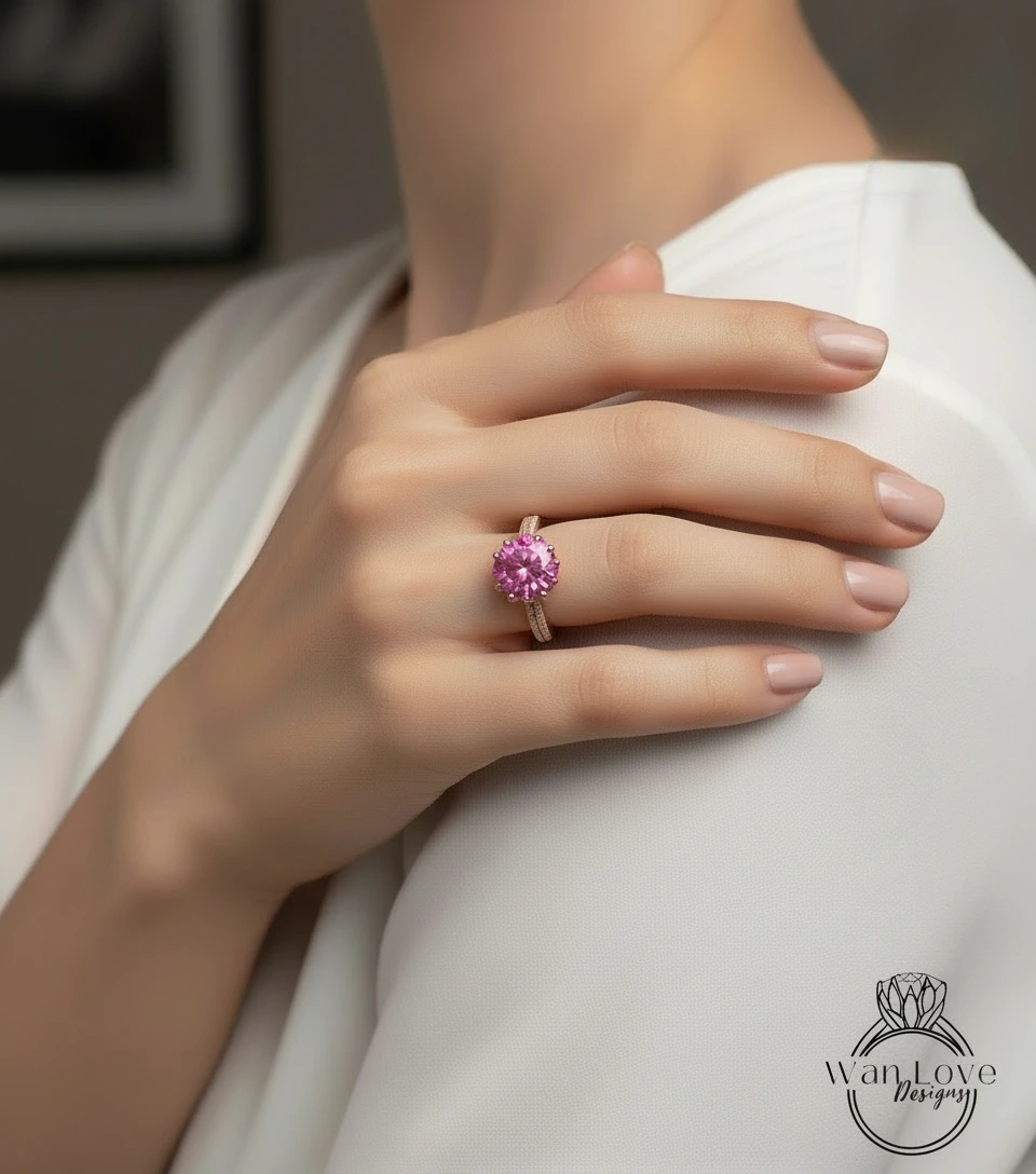 A close-up of a person's hand wearing a pink gemstone ring on the ring finger.