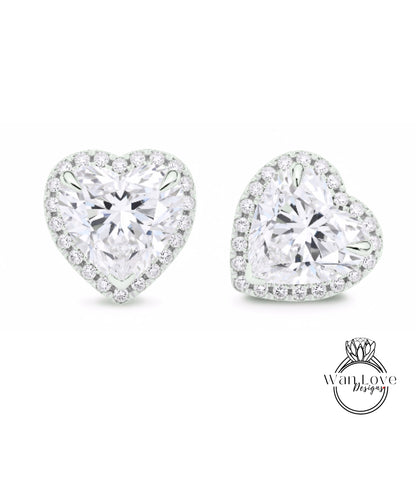 two diamond earrings with a heart-shaped design and a halo of smaller diamonds around the center.