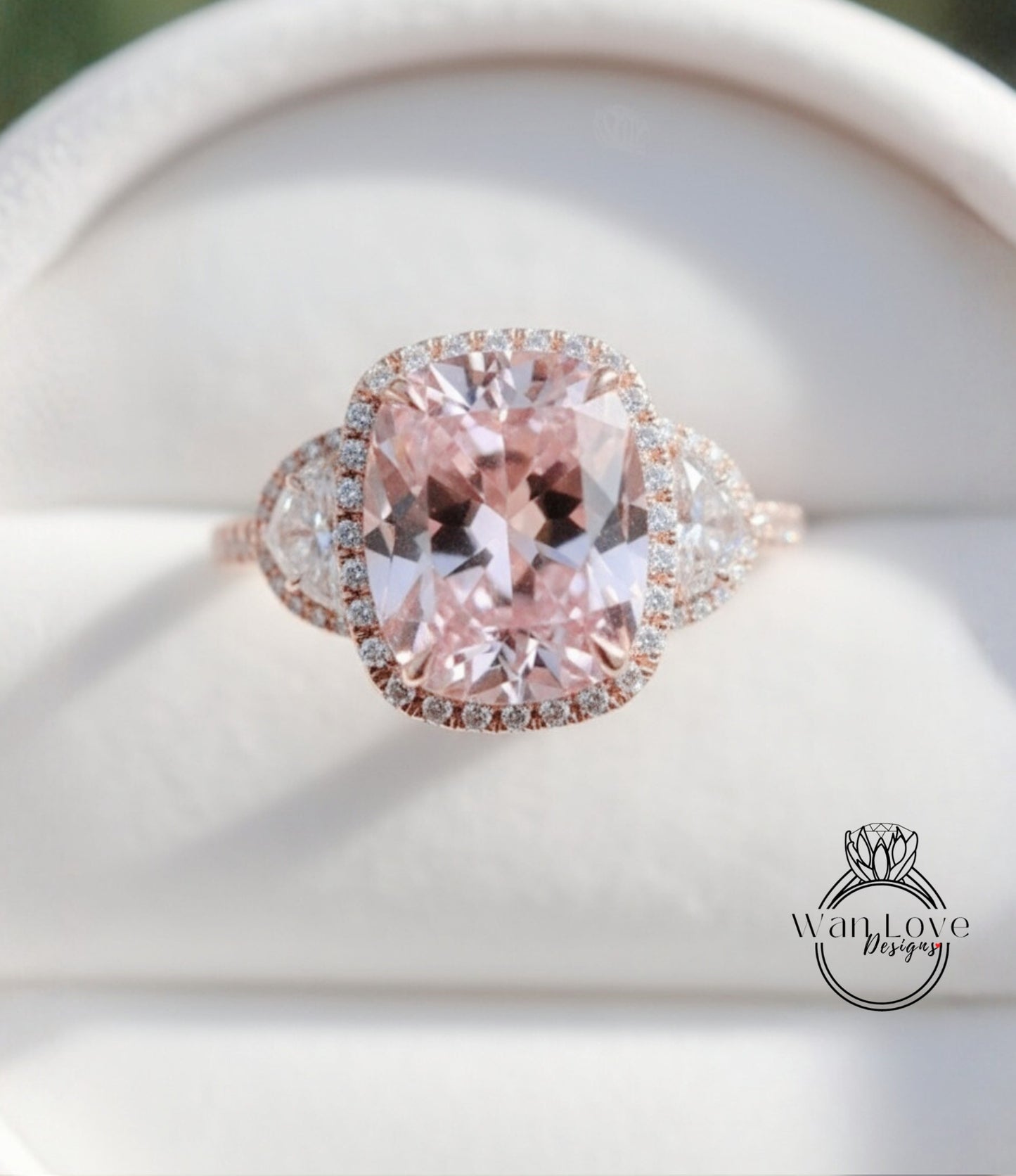 A close-up image of a beautiful pink gemstone ring with a halo of smaller diamonds around the center stone.