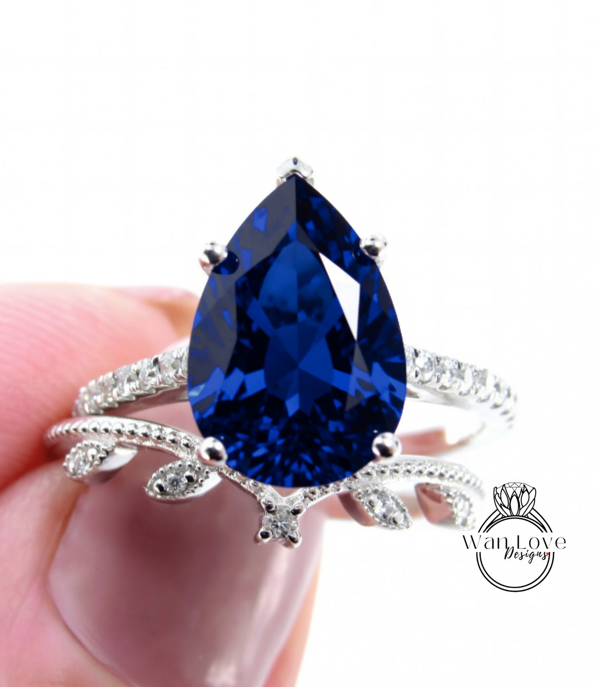 A close-up image of a person's hand holding a silver ring with a large blue gemstone, likely a sapphire or blue topaz.