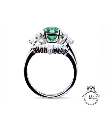 A silver ring with a large green gemstone, surrounded by smaller diamonds, is shown against a white background.