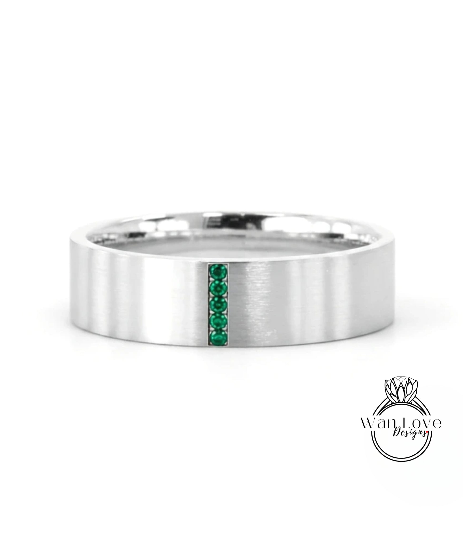 A silver-colored ring with a vertical band of green gemstones.