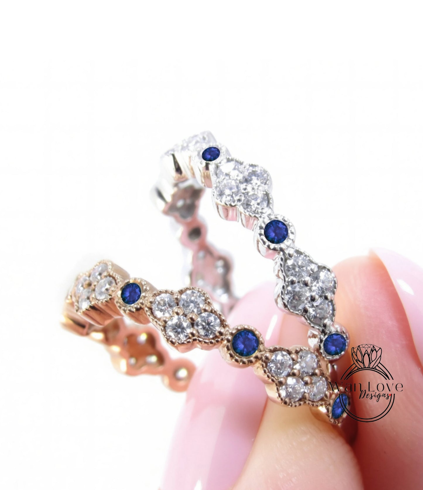 A close-up of a person's hand holding a ring with a row of diamonds and blue gemstones.