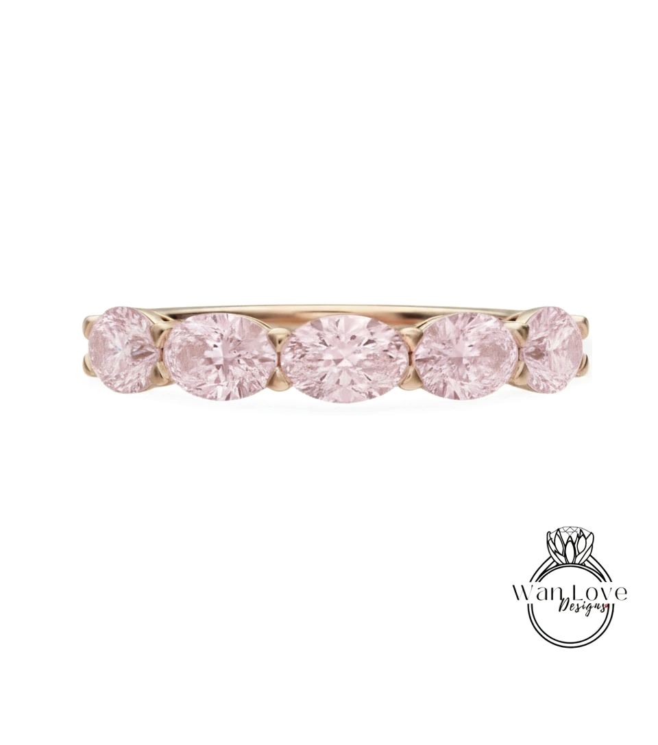 A gold ring with a row of pink diamonds set in it.