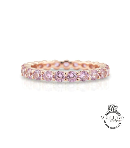 A delicate gold band ring adorned with a row of pink gemstones, creating a beautiful and elegant piece of jewelry.