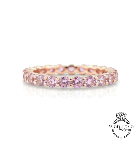 A delicate gold band ring adorned with a row of pink gemstones, creating a beautiful and elegant piece of jewelry.