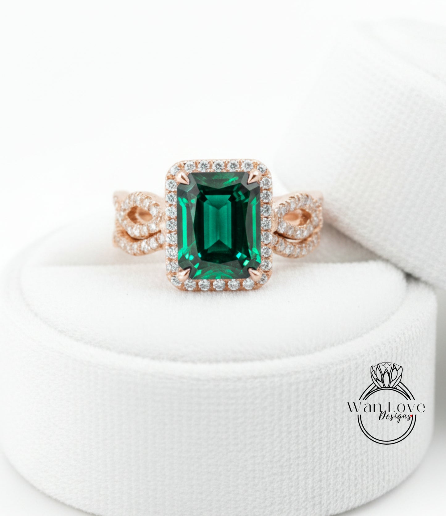 A large, green gemstone ring with a halo of smaller diamonds around it, displayed on a white background.