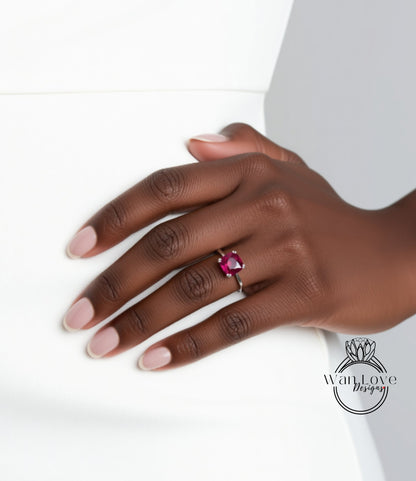 A close-up of a hand wearing a ring with a large, vibrant red gemstone.