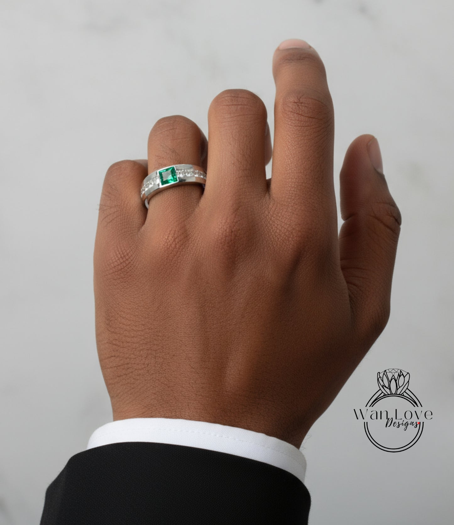 A close-up of a person's hand wearing a ring with a green gemstone.