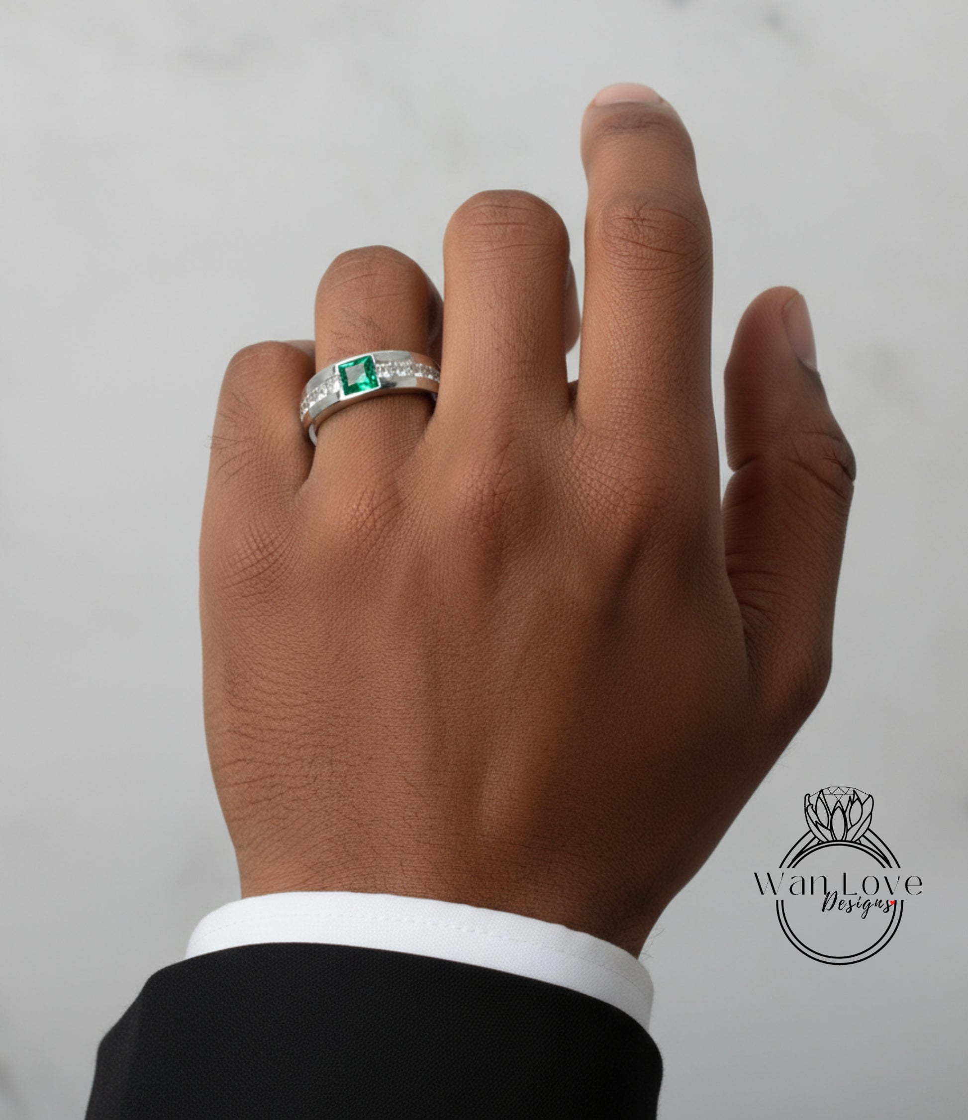 A close-up of a person's hand wearing a ring with a green gemstone.