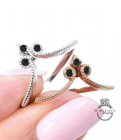 A close-up image of a person's hand holding two rings, one silver and one gold, with black gemstones.