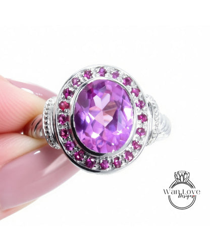 A close-up of a hand holding a ring with a large oval-shaped purple gemstone surrounded by smaller purple gemstones.