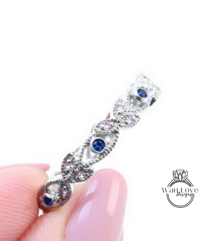 A close-up of a person's hand holding a silver ring adorned with blue gemstones.
