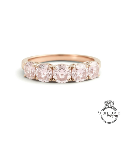 A gold ring with a row of pink diamonds set in the band.