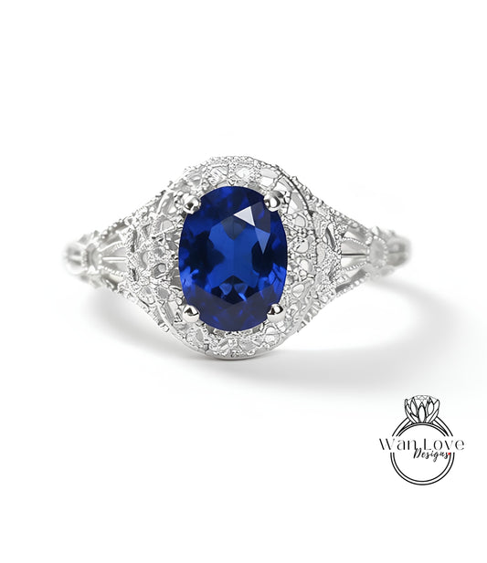 A close-up image of a silver ring with a large blue gemstone, possibly a sapphire, set in a decorative metal band.