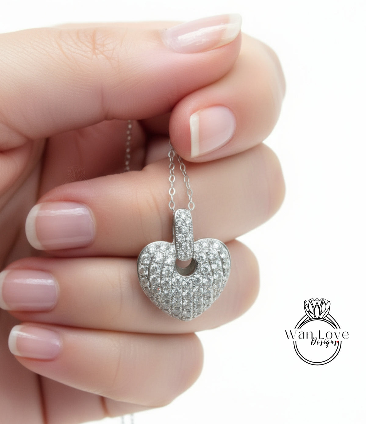 A hand holding a heart-shaped pendant necklace with sparkling diamonds.