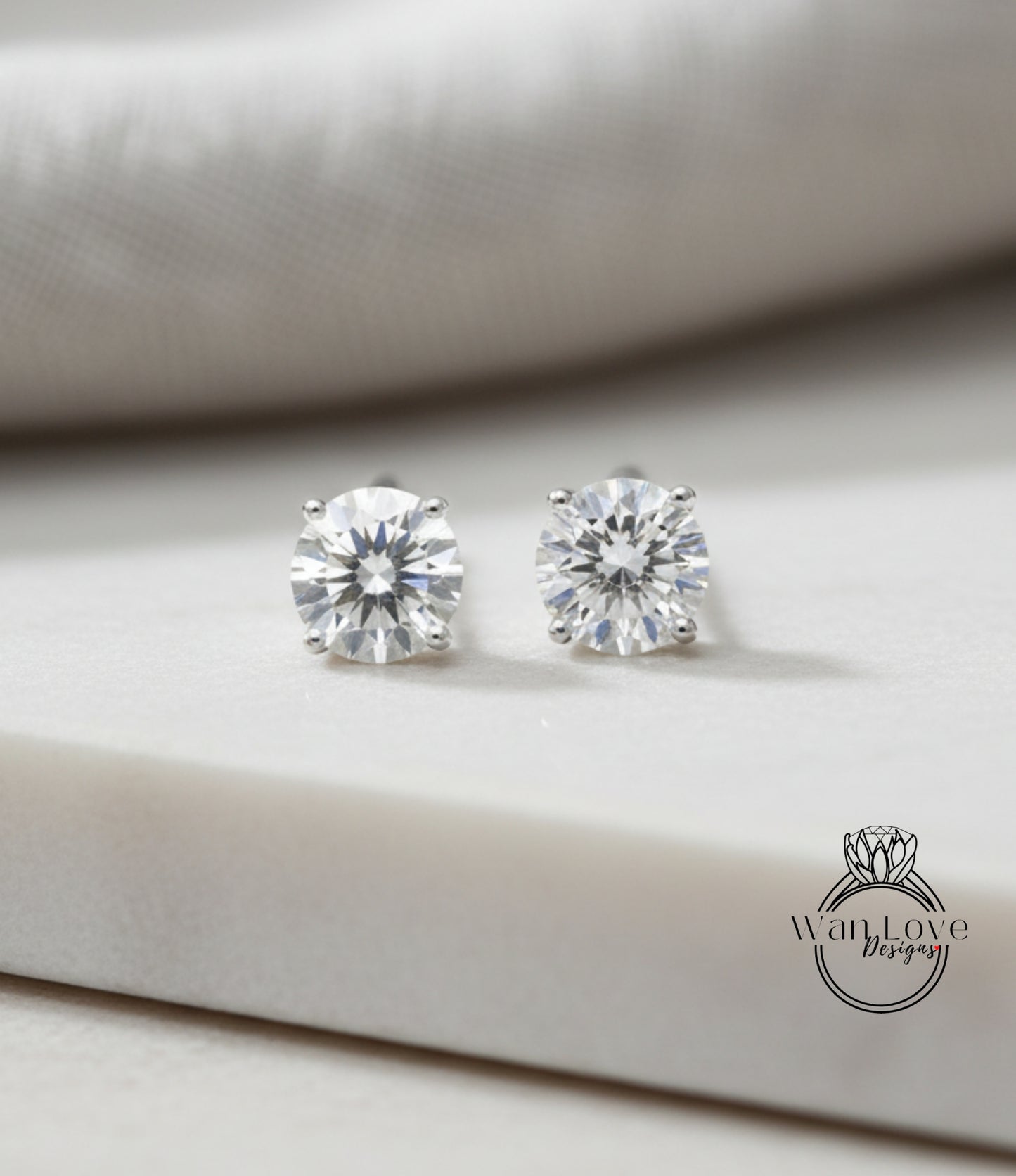 A pair of elegant diamond earrings with large, clear gemstones resting on a white surface.