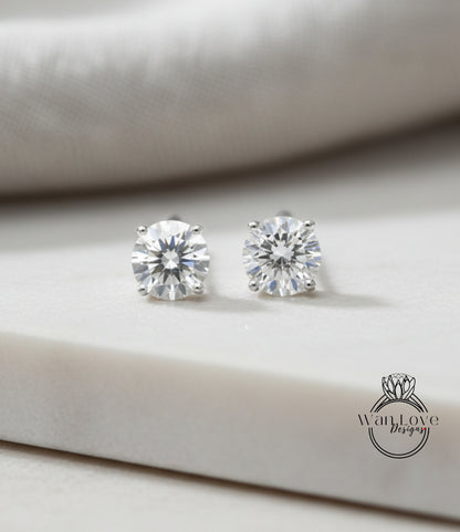 A pair of elegant diamond earrings with large, clear gemstones resting on a white surface.