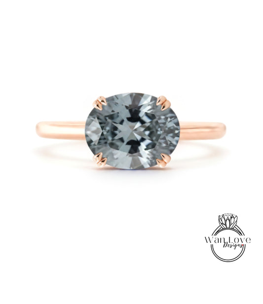 A rose gold engagement ring with a large, round, gray gemstone set in the center.